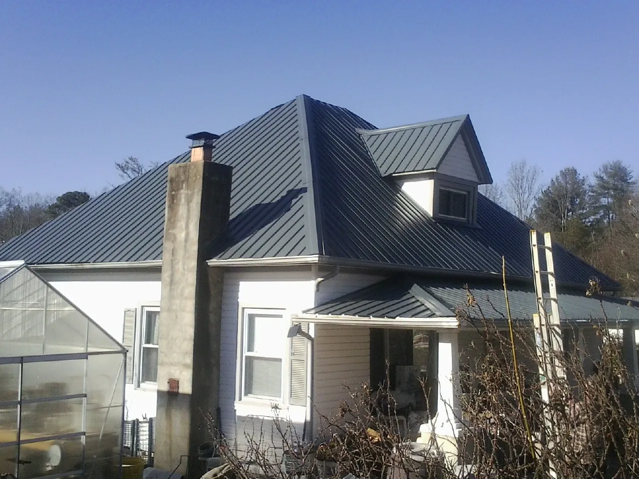 Dark blue standing seam metal roof on a white farmhouse with dormer — Slate & Tile Roof Repair by Roofing Brothers in Yreka