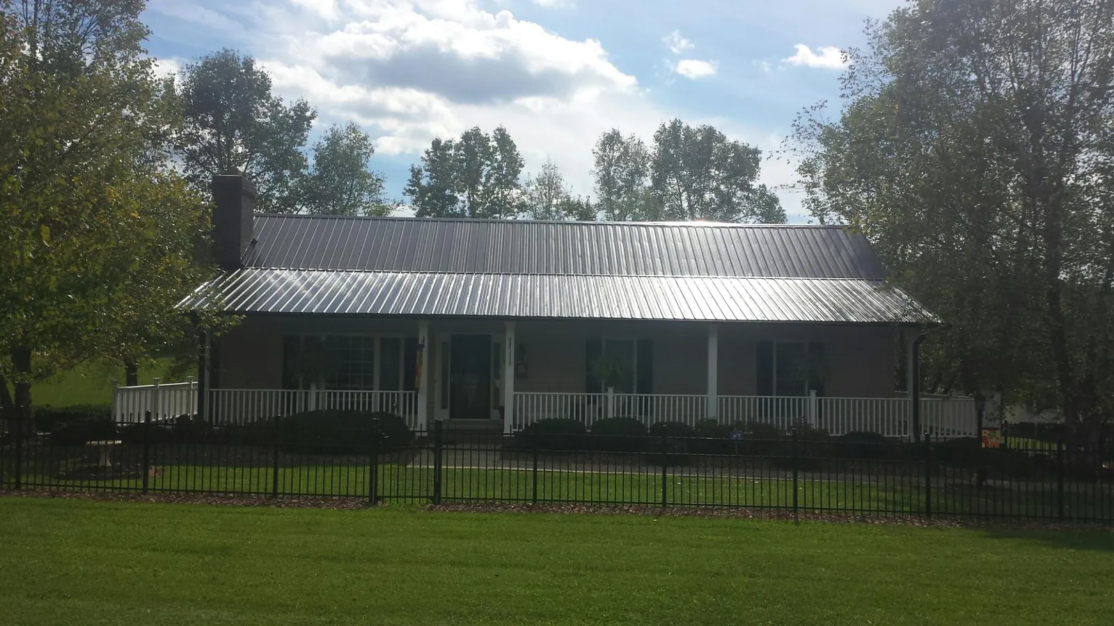 Gray metal roof on a brick ranch with a full width front porch — Gutter Guard Installation work by our crew in Yreka