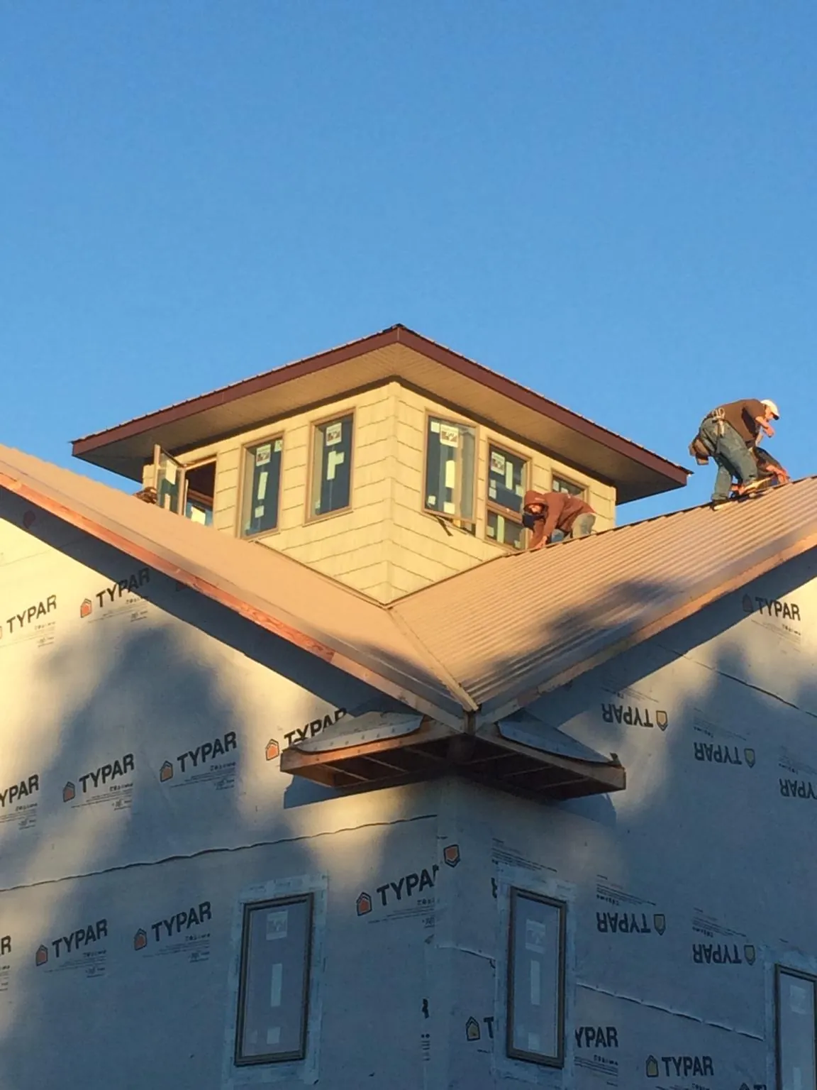 Roofers working around a rooftop cupola on a new metal roof at sunset — Roof Waterproofing in Yreka by Roofing Brothers